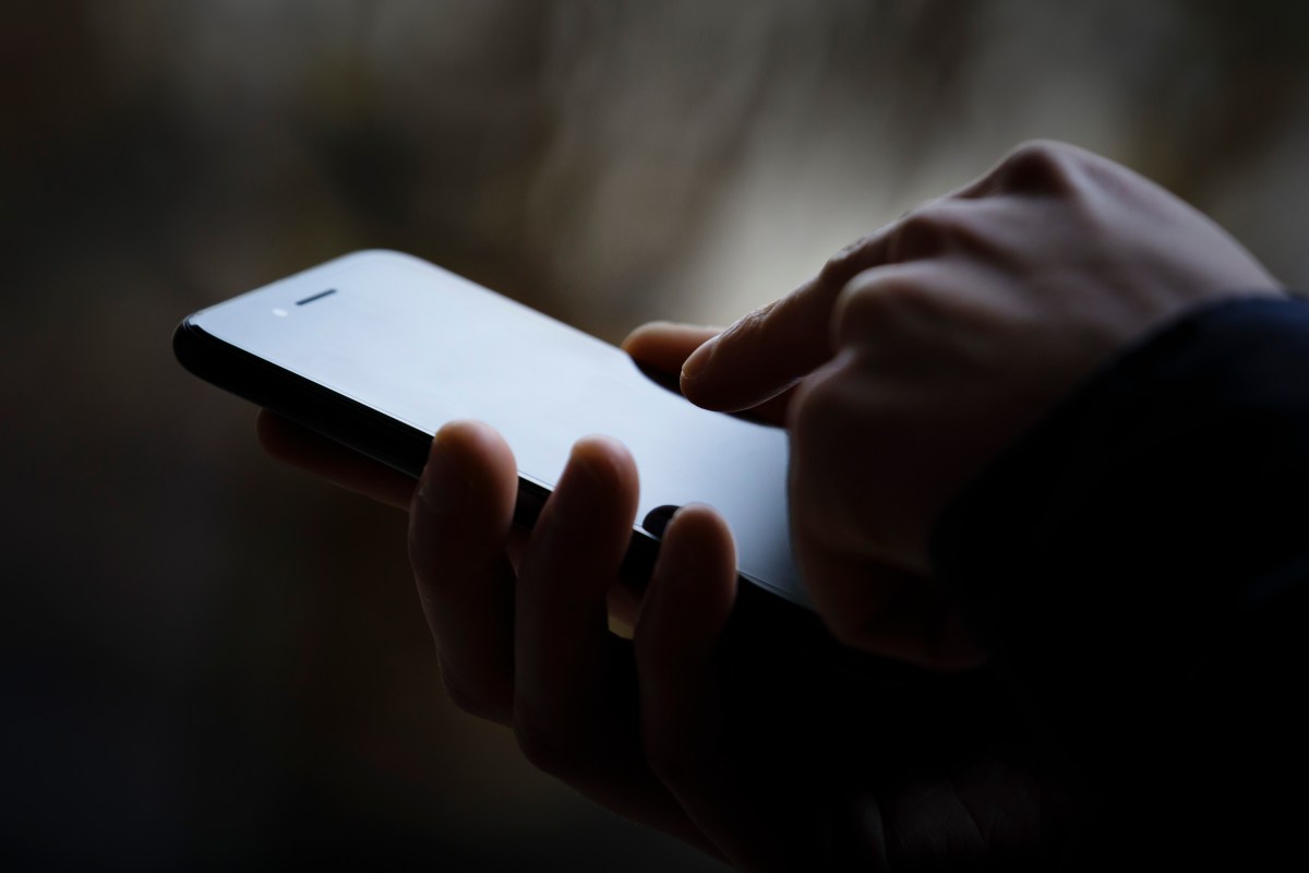 A photo of a person's phone in someone's hand, the image is darkened.